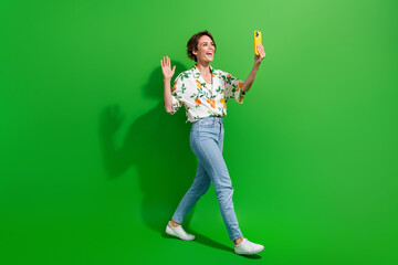 Full length body photo of charming young blogger recording video going waving palm hi symbol...