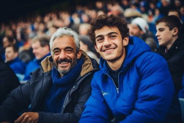 happy smiling father and son are soccer fans cheering their national team in blue on stadium