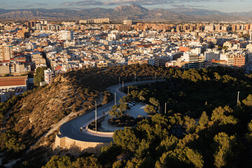 Winding path on a hill at sunset with Alicante in the background.