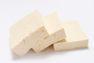 A sliced pieces of tofu on white background close-up, side view.