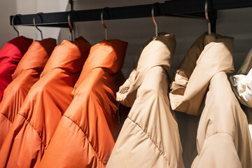 Winter down jackets hanging on hangers in the store close-up, side view. © TATIANA KIM