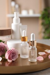 Fototapeta na wymiar Bottles of cosmetic serum, beauty products and flowers on table indoors
