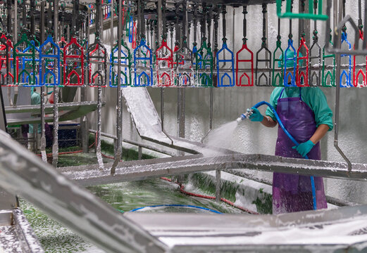 Worker spray foam cleaning machine in poultry factory.