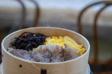 湯気が立つ肉と錦糸卵の蒸しご飯