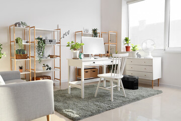 Comfortable workspace with modern computer and portable power station in contemporary room