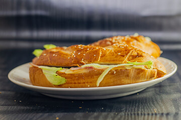studio photography of sandwich on dark background with open bread with cheese ham lettuce and mayonnaise on a plate for breakfast