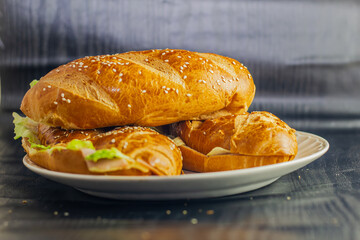studio photography of sandwich on dark background with open bread with cheese ham lettuce and mayonnaise on a plate for breakfast