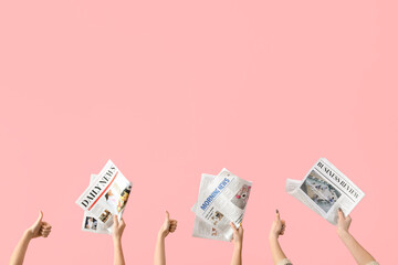 Women with newspapers showing thumbs-up on pink background