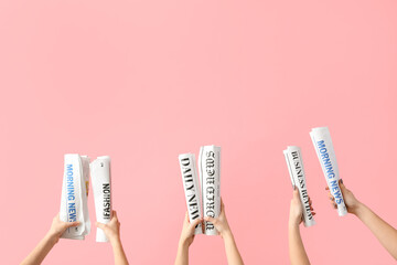 Women with rolled newspapers on pink background