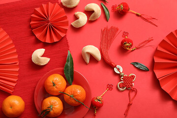 Composition with paper fans, tangerines, fortune cookies and Chinese symbols on red background. New Year celebration