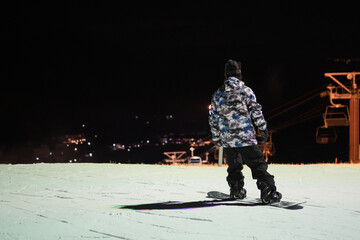 冬の夜にナイターのスノーボードをする人の顔無しの全身