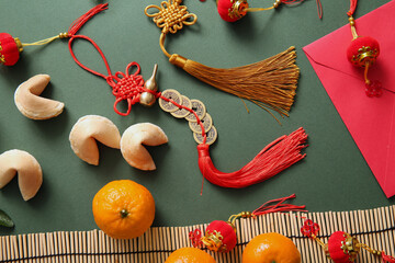 Composition with fortune cookies, tangerines and Chinese symbols on green background. New Year...