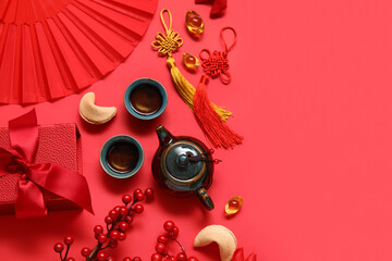 Teapot with cups of tea, fortune cookies and different Chinese symbols on red background. New Year celebration