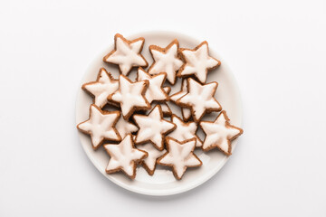 Plate with star-shaped gingerbread cookies on white background