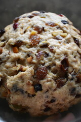 Bread dough mixed with rum-soaked dried fruits and nuts is rest in a bowl.