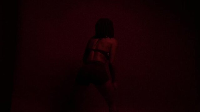 Slow motion of temperamental and empowered dancer under red lights