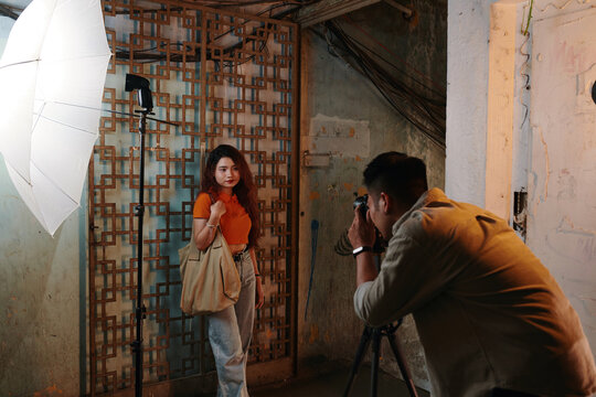 Young man photographing girl in old building for online clothing store