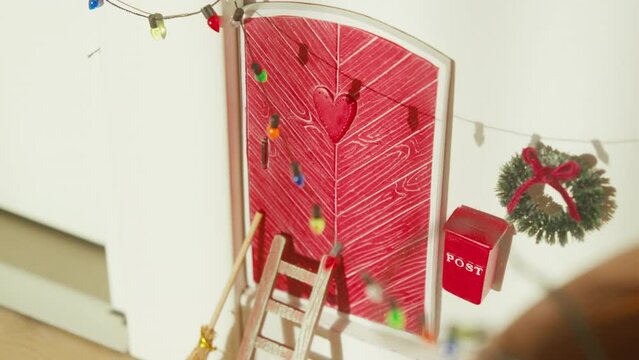 Cute Scandinavian elf door adorned for Christmas with lights and wreath.