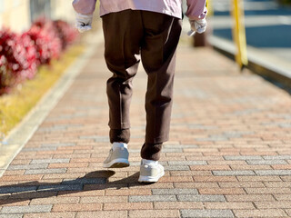 住宅街の歩道を歩く高齢女性の足元