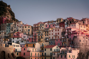 Fototapeta na wymiar Picturesque row of houses in varying shades of pink perched atop a steep hillside in a quaint town