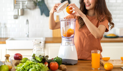 Portrait of beauty healthy asian woman making orange fruit smoothie with blender.girl preparing cooking detox cleanse with fresh orange juice in kitchen at home.health, vitamin c, diet, healthy drink