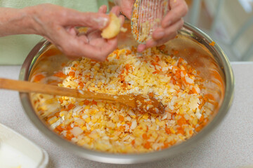 Old lady making a vegetable food in metal bowl. Cutting veggies for salad.