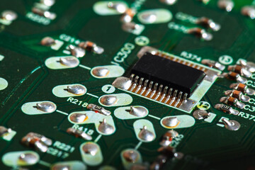 Micro chip and capacitors mounted on a green printed circuit board, close up