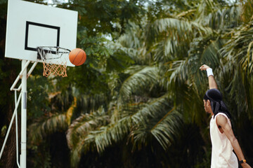 Accurate streetball player throwing ball in basket at outdoor court