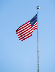 waving USA flag on pole against blue sky