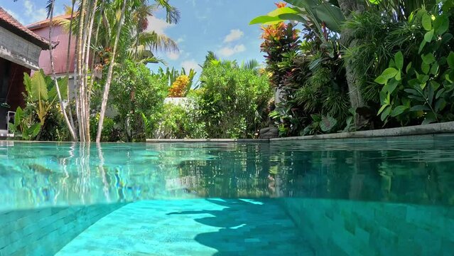Half underwater shot. Luxury villa surrounded by lush greenery. Holidays concept