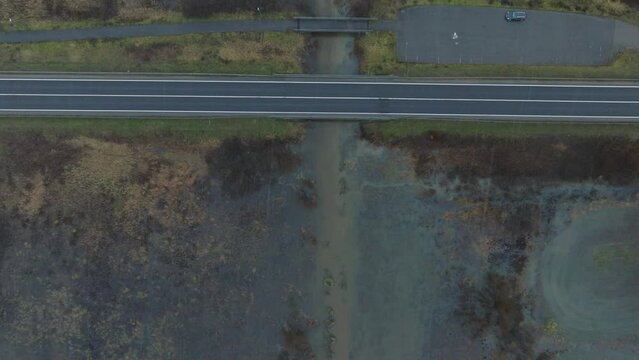 Aerial establishing view of high water, Durbe river (Latvia) flood, brown and muddy water, agricultural fields under the water, overcast winter day with light snow, birdseye drone shot moving forward