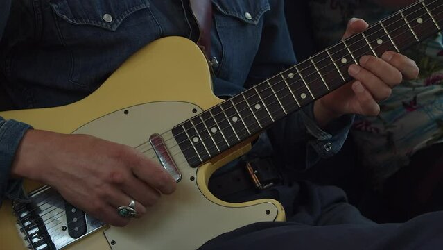 Man plays vintage cream colored Fender Telecaster guitar, close-up