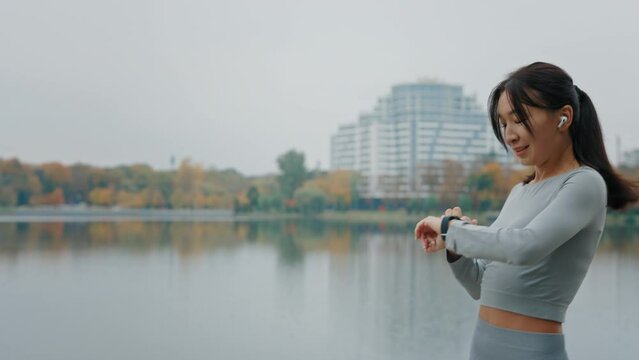 Fitness Asian Woman Running and Looking at Smartwatch Outdoors to Calculate the Calories. Athlete Workout Equipment App Technology Active Device. Sport Gadget Technology