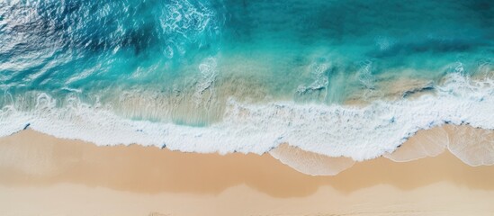 Fototapeta na wymiar Bird's-eye view of serene sandy beach with clear blue ocean.
