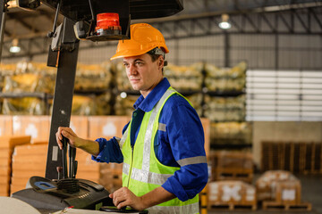 Portrait of Caucasian warehouse worker sitting in forklift machine Professional male industry factory engineers wear helmets and process orders and products at the manufactory warehouse.