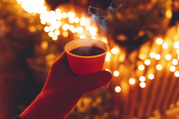 Mulled wine in the hands of a girl during a snowfall in the forest. Winter hot drinks with aromatic...