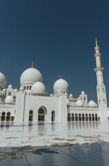 Fototapeta na wymiar view of Sheikh Zayed Grand Mosque huge tall minarets in white marble muslim symbol and several domes over clear blue sky in uae
