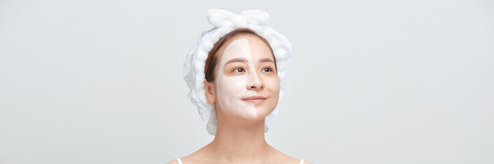 an attractive young girl with a pink towel on her head applied a clay useful mask to half the face