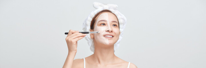 Banner of woman with a towel on her head apply a cleansing clay mask on her face - 698460930