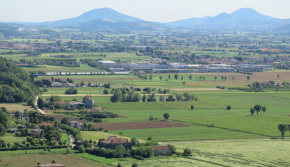 view from above of the cultivated fields with regular geometric shapes in the plain with the mountains in the background - obrazy, fototapety, plakaty