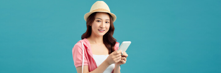Happy traveler Asian woman joy relaxing on summer vacation holding smartphone on blue background.