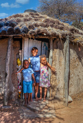 african kids in front of a hut with a thatched roof