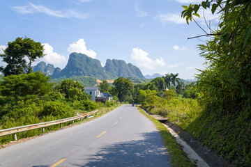 An asphalt road in the middle of the countryside and mountains, in Asia, in Vietnam, in Tonkin, towards Hanoi, in Mai Chau, in summer, on a sunny day.