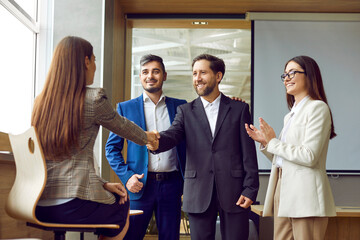 Business people greet each other as they meet in the office. Happy man and woman shake hands as...