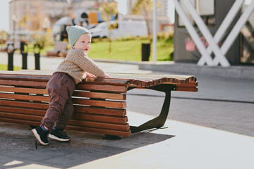 Portrait of lonely child boy on a park bench. Baby on a walk