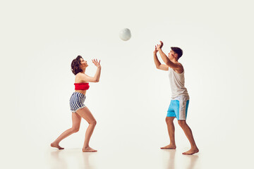 Young people, man and woman, friends playing beach volleyball, having fun on seaside resort against...