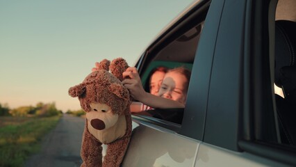 little girl with toy bear. happy face child daughter from window with teddy bear. happy family. mother daughter traveling car. happy mother child back seat car going trip. face childish smile. - obrazy, fototapety, plakaty
