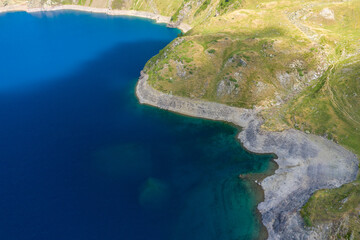 The blue lake in the green countryside in the mountains , Europe, France, Occitanie, Hautes-Pyrenees, in summer on a sunny day.