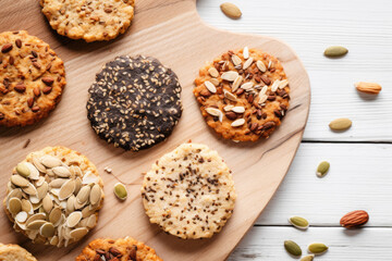 Different types of healthy cookies with nuts and seeds on the wooden board - obrazy, fototapety, plakaty