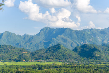Fototapeta na wymiar A city in the valley among green rice fields and green mountains, Asia, Vietnam, Tonkin, between Son La and Dien Bien Phu, in summer on a sunny day.